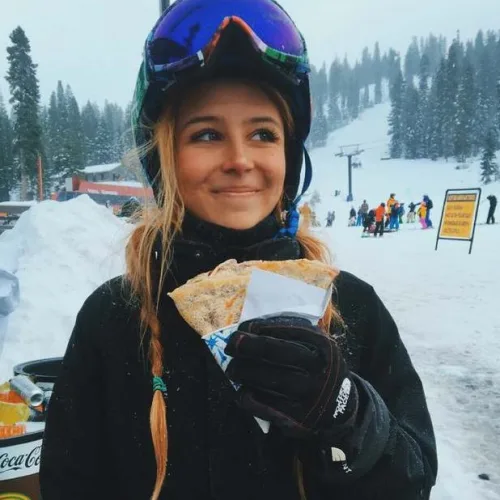 Une monitrice de ski mange une crèpe aux pieds des pistes